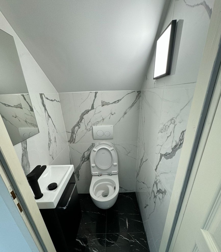 WC rénové à Cessy, carrelage effet marbre blanc et sol noir — Pro Innovation EB