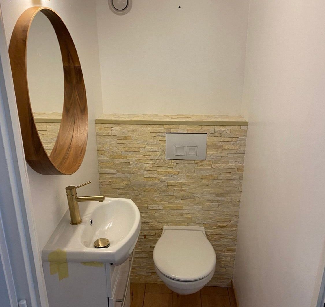 WC rénové à Évian avec parement pierre et miroir rond en bois — Pro Innovation EB
